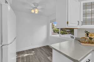 Kitchen featuring freestanding refrigerator, decorative backsplash, white cabinetry, light wood-style floors, and ceiling fan