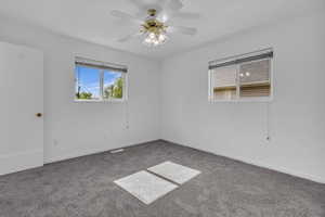 Carpeted spare room featuring ceiling fan and baseboards