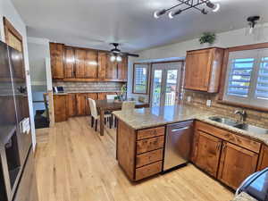 Kitchen featuring brown cabinetry, appliances with stainless steel finishes, decorative backsplash, ceiling fan, and light wood finished floors