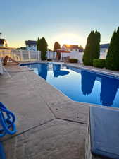 Pool at dusk featuring a fenced backyard and a patio