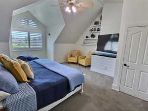 Carpeted bedroom featuring vaulted ceiling and a ceiling fan
