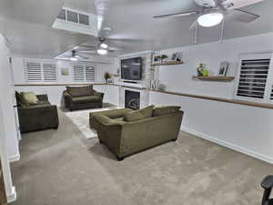 Living room with a ceiling fan, carpet floors, and a fireplace