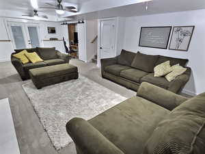 Living area with ceiling fan, stairs, french doors, and a barn door