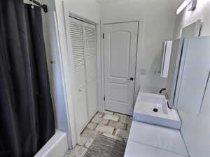 Bathroom with a closet, vanity, and shower / tub combo with curtain