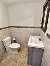 Bathroom featuring tile walls, vanity, and wainscoting