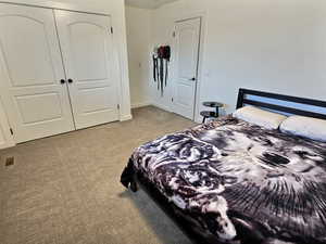 Bedroom with light colored carpet and a closet