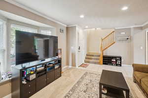 Living area with light carpet, stairway, crown molding, a textured ceiling, and recessed lighting
