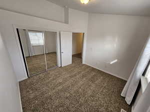 Unfurnished bedroom featuring dark carpet, a closet, and a high ceiling