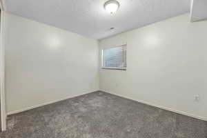 Spare room featuring dark colored carpet and baseboards