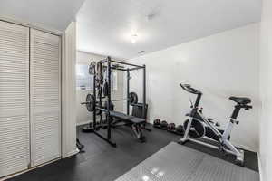 Exercise area featuring a textured ceiling and baseboards
