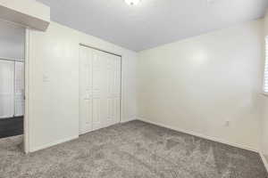 Unfurnished bedroom with carpet floors, a closet, and a textured ceiling