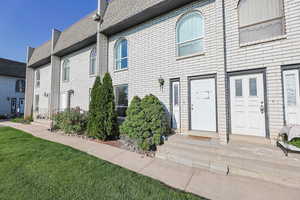 View of front facade with brick siding, a front yard, and a shingled roof