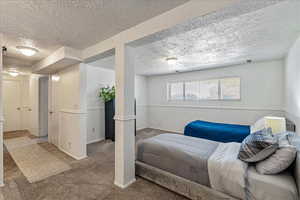 Bedroom featuring a textured ceiling, carpet floors, and a textured wall