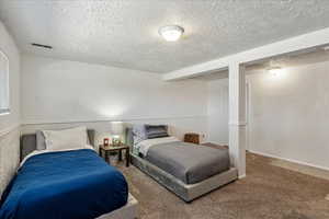 Carpeted bedroom with a textured ceiling and baseboards