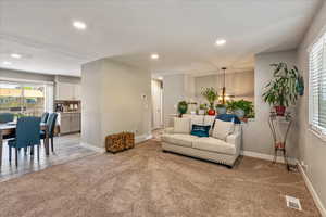 Living room with light colored carpet, recessed lighting, plenty of natural light, and a chandelier