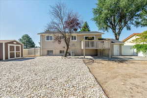 Back of house featuring a storage unit and a wooden deck