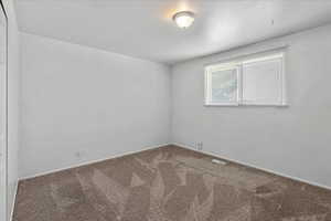 Carpeted spare room featuring baseboards