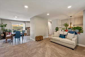 Living area featuring light carpet, recessed lighting, and a chandelier