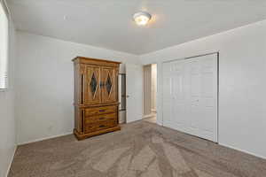 Carpeted bedroom featuring a closet and baseboards