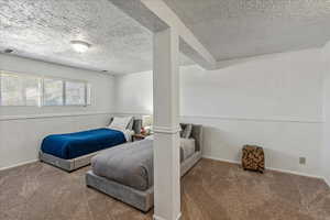 Bedroom with carpet floors, a textured ceiling, and a textured wall