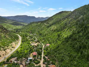 Aerial view of property and surrounding area with a forest and a mountainous background