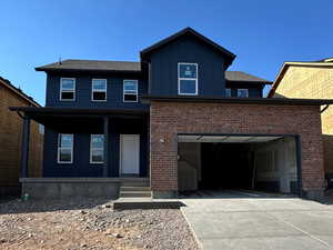 View of front facade with driveway, board and batten siding, and covered porch