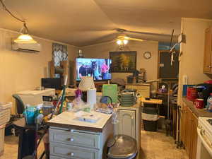 Kitchen featuring ceiling fan, white stove, open floor plan, fridge, and lofted ceiling