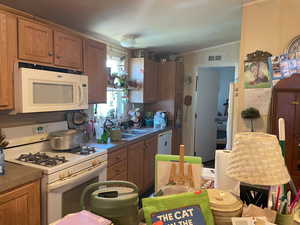 Kitchen with white appliances, brown cabinets, and ornamental molding