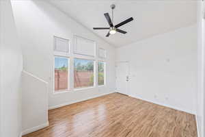 Unfurnished room with high vaulted ceiling, light wood-type flooring, and a ceiling fan