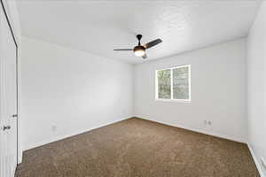 Carpeted empty room featuring ceiling fan and a textured ceiling