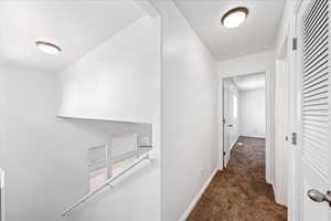Corridor featuring carpet floors and baseboards