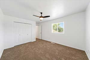 Unfurnished bedroom with carpet, a closet, and a ceiling fan