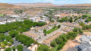 Aerial view of property and surrounding area featuring a mountainous background and nearby suburban area