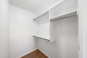 Walk in closet featuring dark colored carpet