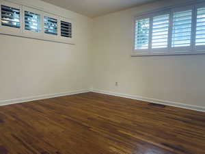 Unfurnished room with dark wood-style flooring and baseboards