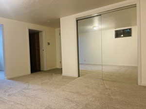 Unfurnished bedroom featuring carpet flooring, a textured ceiling, and a closet