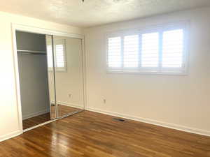 Unfurnished bedroom with wood-type flooring, a closet, and a textured ceiling