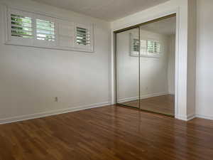 Unfurnished bedroom with wood finished floors and a closet