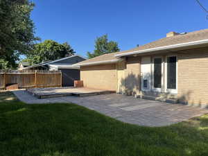 Back of property with roof with shingles, brick siding, a patio, and a chimney