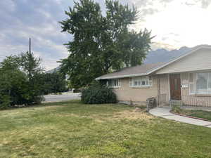 View of side of home featuring a yard, brick siding, and a shingled roof