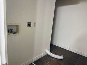 Laundry room featuring hookup for an electric dryer, dark tile patterned flooring, and washer hookup