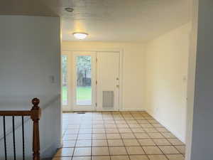 Foyer entrance with light tile patterned floors and a textured ceiling