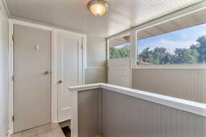 Corridor with light tile patterned flooring and a wainscoted wall