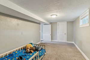Unfurnished bedroom with a textured ceiling, carpet flooring, and a textured wall