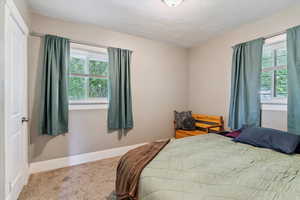 Carpeted bedroom featuring baseboards and a textured ceiling
