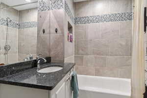 Full bath featuring vanity, shower / bath combination with curtain, and tile walls