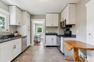 Kitchen with stainless steel appliances, white cabinetry, dark stone countertops, and light tile patterned flooring