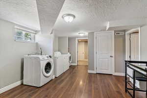 Laundry area with washing machine and clothes dryer, a textured ceiling, and dark wood finished floors