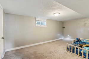 Unfurnished bedroom with carpet floors, a textured ceiling, and a textured wall