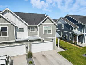 View of front of house with board and batten siding, driveway, a garage, a shingled roof, and a front yard